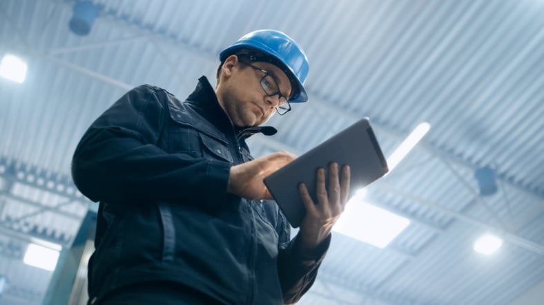Man wearing hard hat holding a tablet