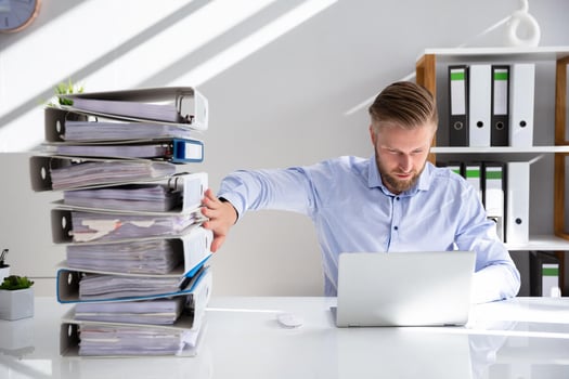 Digital transformation consulting: consultant balancing a stack of documents while typing