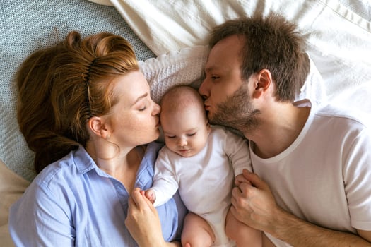 Mother and father kissing their baby, enjoying their parental leave