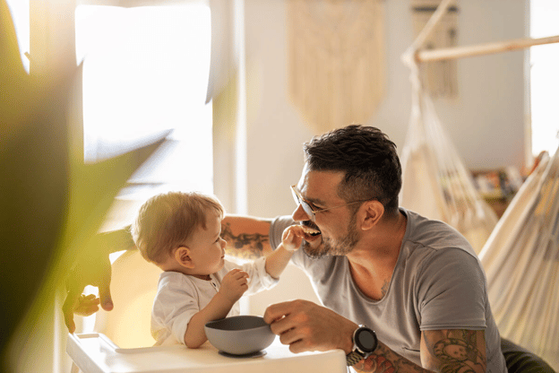 Paternity leave FMLA: father happily feeding his child