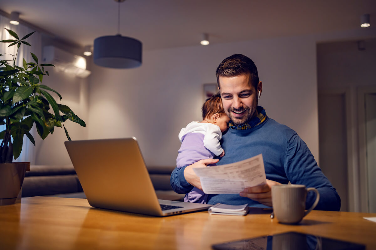 Paternity leave FMLA: father carrying his baby while working at home